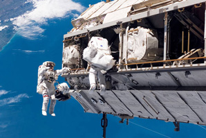 Two astronauts during a space walk, working collaboratively floading above the earth