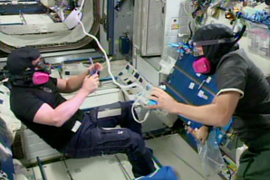 Two astronauts working collaboratively to identify and repair air leaks